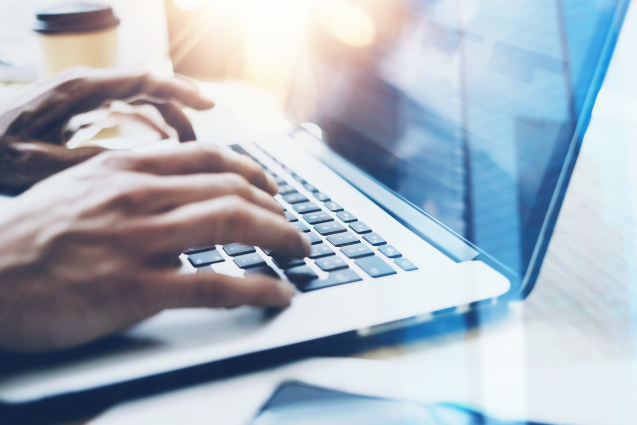 Closeup view of businessman working at sunny office on modern laptop.Male hands typing on notebook keyboard.Blurred background.Sunlight effects.